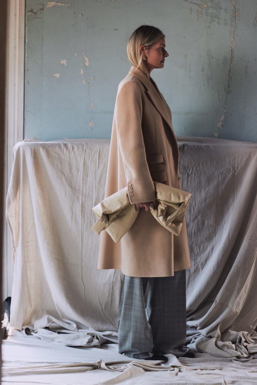 Woman wearing camel coat against blue wall